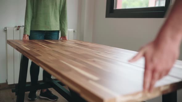 People Placing Wooden Table Top Onto Assembled Metal Table Legs And Support. DIY Table. medium shot