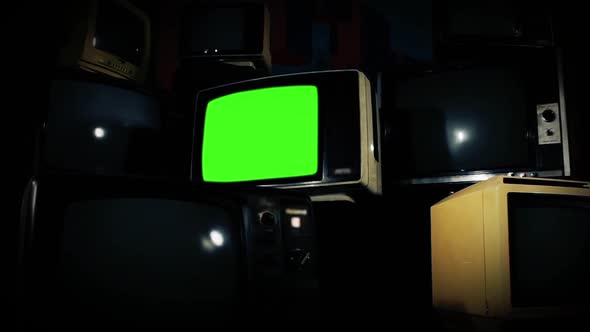A Retro TV Set with Green Screen Surrounded by Many Retro TVs. Zoom In.