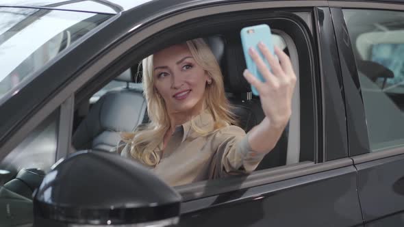 Pretty Blond Caucasian Woman Taking Selfie in the Salon of New Car