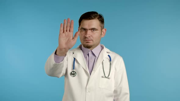 Portrait of Serious Doctor in Professional Medical White Coat Showing Rejecting Gesture By Stop Palm