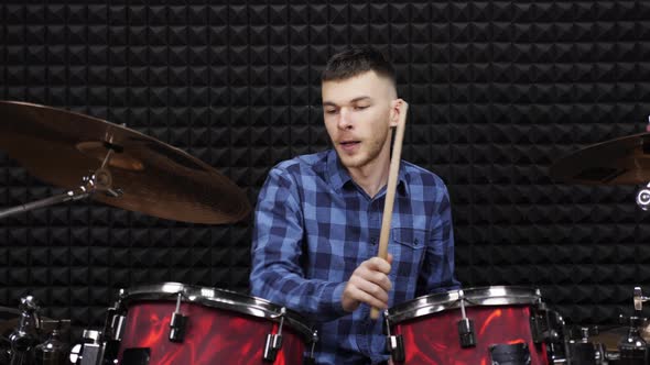 Drummer is playing on drum kit on stage in professional recording studio