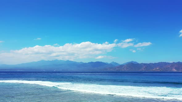 Wide angle fly over clean view of a sandy white paradise beach and aqua blue ocean background in col