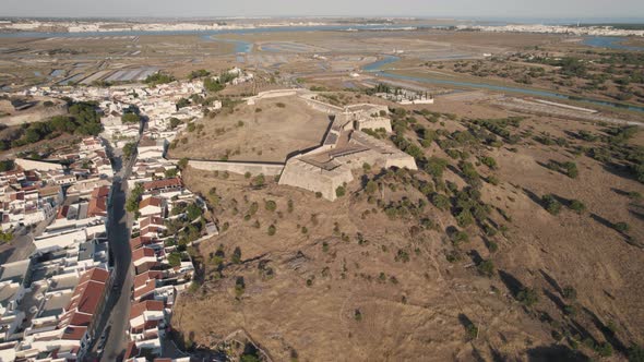 Hilltop Castro Marim Castle, fortress overlooking town and salt plans. Aerial forward