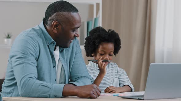 Caring African American Father Helping Little Daughter Schoolgirl Do Homework Adult Parent or Tutor