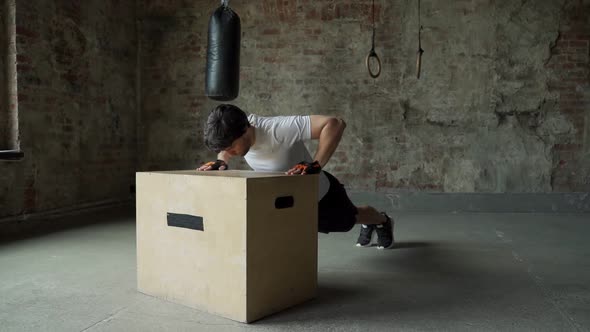 A Man Working Out in the Gym Does Pushups From a Wooden Box