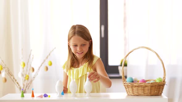 Happy Girl Decorating Easter Eggs at Home