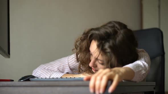 Tired Young Woman with Curly Hair and White Shirt is Working at the Office Using Her Laptop Routine