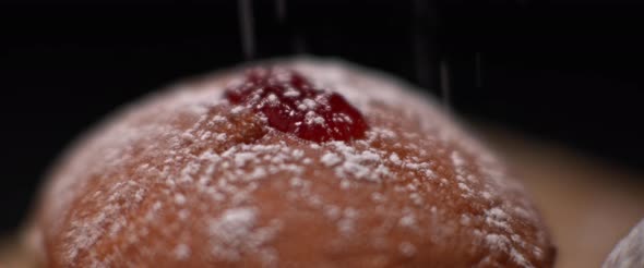 Sprinkling sugar powder on hanukkah jelly doughnut, slow motion