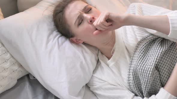 Top View of Coughing Young Woman in Bed