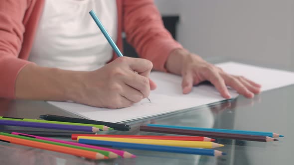 Young Asian Pregnant woman drawing baby in belly and family in notebook