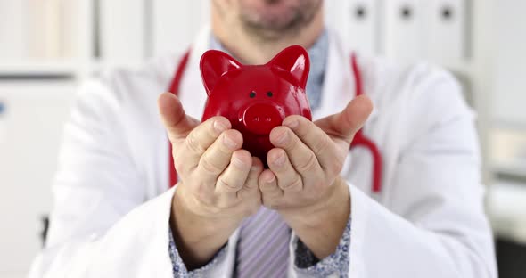 Young Smiling Male Doctor Holds Piggy Bank in Hands Slow Motion  Movie