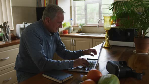 Senior man using laptop and mobile phone at home