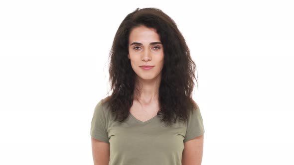 Portrait of Caucasian Calm Female with Dark Curly Hair Posing with Kind Smile Isolated Over White