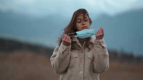 Slow Motion Tired Woman Took Off Protective Mask Raising Hands on Nature in Mountains