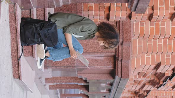 African American Girl Sitting on Stairs Holding Paper Map Planning Route Searching Hotel Building