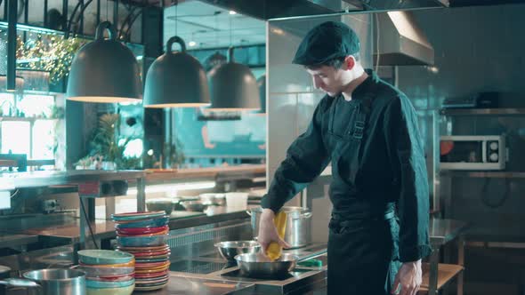 Young Cook is Adding Sauce to a Dish in the Restaurant