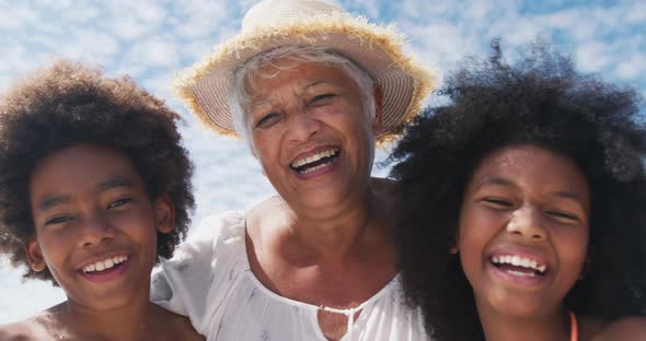 Portrait of mixed race senior woman with grandchildren smiling at the beach