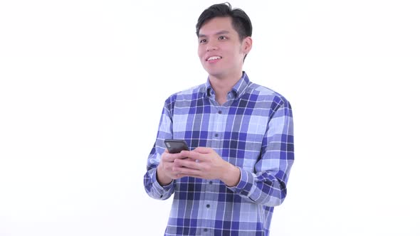 Happy Young Asian Hipster Man Thinking While Using Phone