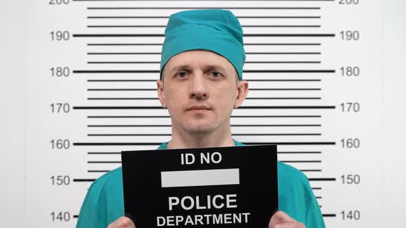 Mugshot of a Surgeon in Green Clothes, at the Police Station