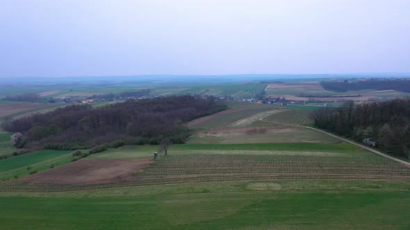 Flying above rural landscape with hills and cultivated fields in agriculture environment