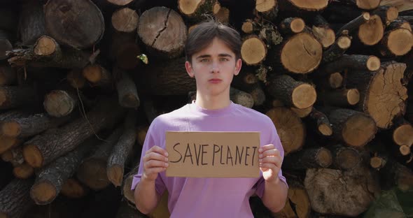 Ecology Concept - Save the Planet Poster. Activist Holding Poster on the Background of Felled Trees