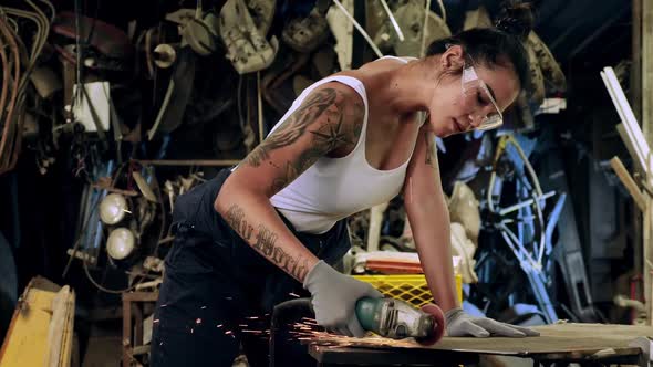 Attractive young woman mechanical worker repairing a vintage car in old garage.