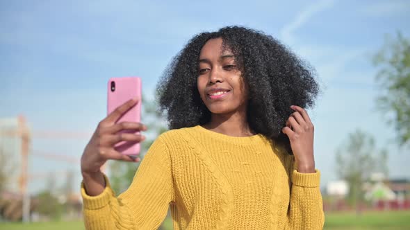 young black african woman in a yellow sweater makes a selfie on the phone