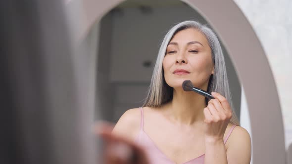 Closeup of Asian Mature Woman Touching Face with Brush