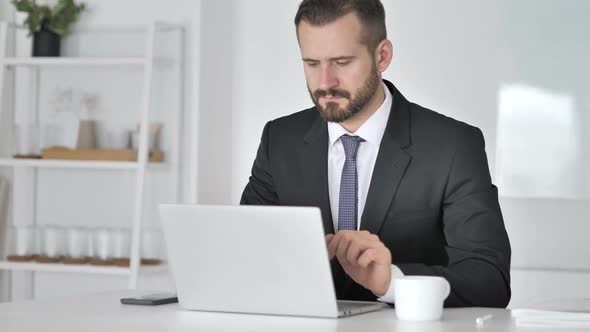 Businessman Leaving Office After Closing Laptop at Work