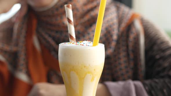 Banana Mango Milk Shake on Table and Young Women in Background