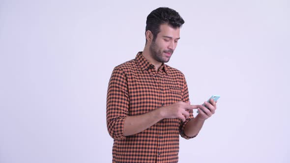 Happy Bearded Persian Hipster Man Using Phone and Looking Surprised