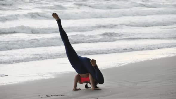 Asian woman is practicing yoga position on the beach.