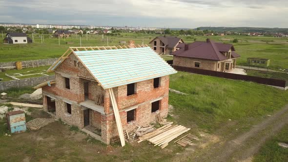 Aerial view of a brick house with wooden roof frame under construction