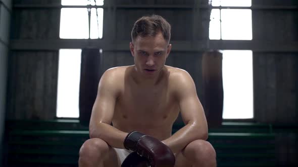 Portrait of Strongwilled Male Boxer in Boxing Gloves and Mouth Guard Concentrating Before Training