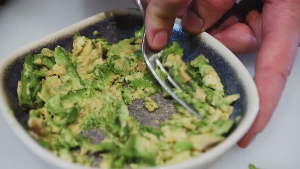Guacamole dip sandwiches making, squeezing avocado using kitchen fork