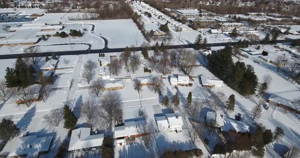 A slowlying forward snowy aerial flyover of a suburban Michigan residential neighborhood on a sunny