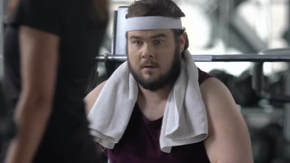 Funny Obese Man Looks Enviously at Athlete People Training in Gym, Insecurities
