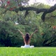 Rear View of Young Woman Performing Asanas Preparing for Meditation Under a Tree in a Green Park - VideoHive Item for Sale
