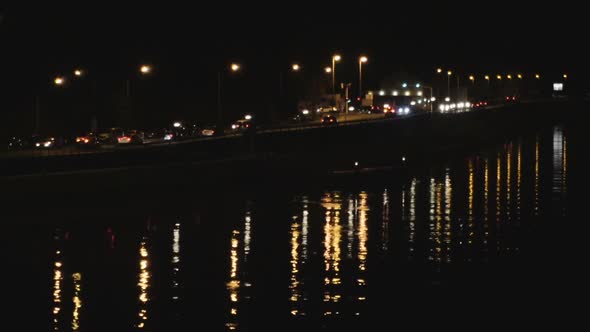 Cars riding along night road near river