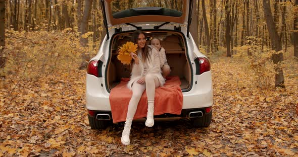 Mother and Daughter Sitting in a Car Trunk