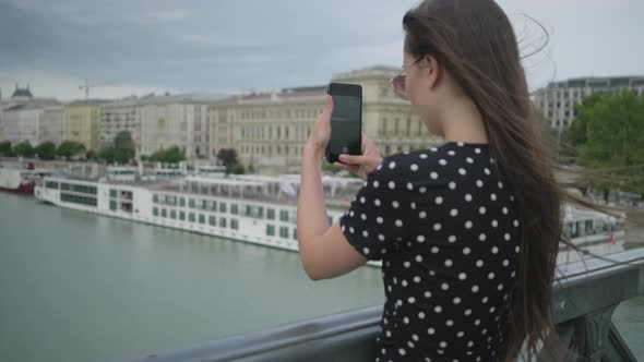 Female Tourist is Photographing By Smartphone Danube River