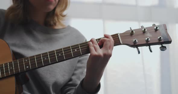 A Teenager in Home Clothes Plays the Guitar Alone