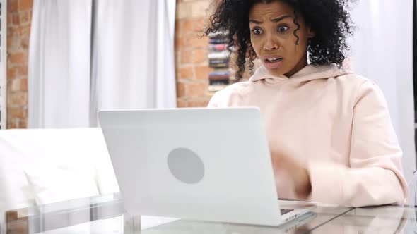 AfroAmerican Woman Sitting on Couch Upset By Loss Working on Laptop