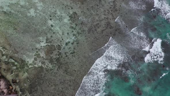 Aerial view of waves crashing into palms and coastline La Digue Seychelles