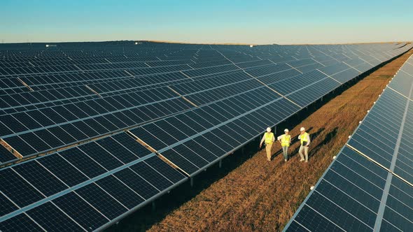 Drone Shot of Three Solar Energy Specialists Having a Discussion at a Solar Power Facility