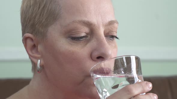 Portrait of Mature Woman with Short Blond Hair Who Drinking Water From the Glass