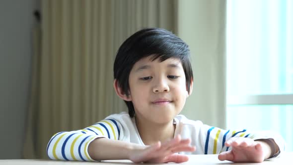 Asian Child Knocks His Fingers On The Table