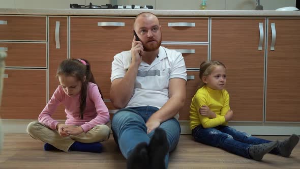 Tired Father Sitting on Floor Talking on the Phone Feels Annoyed Exhausted