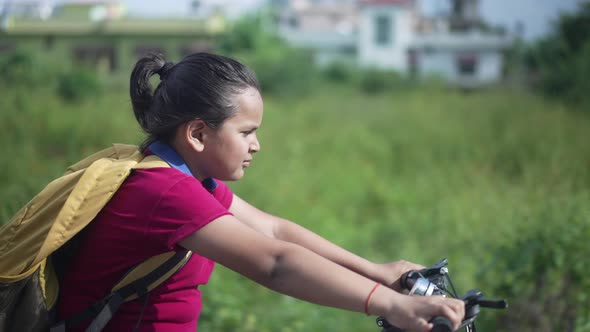 Slowmotion Shot of an Indian Kid Cycling on a Road Near a Sugarcane Field in a Rural Area of
