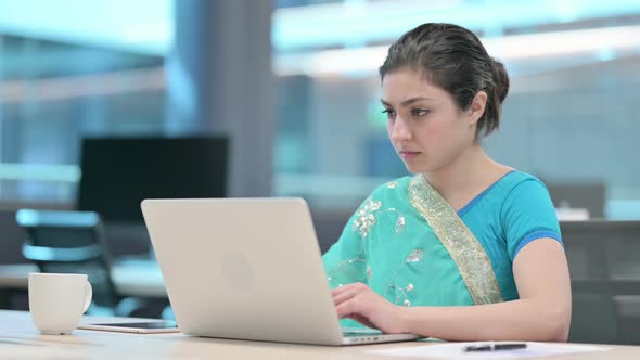 Indian Woman Looking at Camera while using Laptop